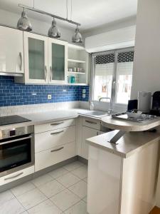una cocina con armarios blancos y azulejos azules en Superbe 3 PIECES face gare TGV / RER de Massy, en Massy