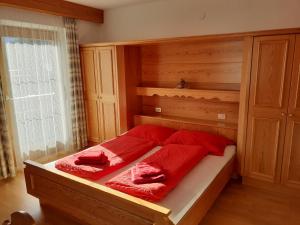 una camera da letto con un letto con cuscini rossi di Apartement Noggler a Malles Venosta