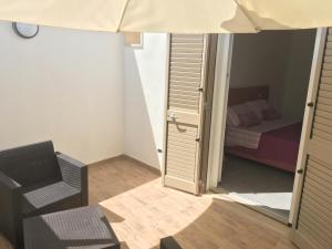 ein Schlafzimmer mit einem Bett, einem Stuhl und einer offenen Tür in der Unterkunft Dear Mary B&B in San Cesario di Lecce