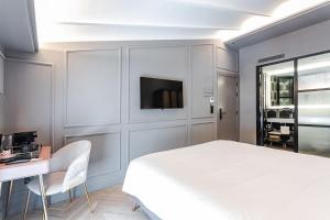 Un dormitorio con una cama, un escritorio y un televisor. en Reina 107 Beach Boutique, en Valencia
