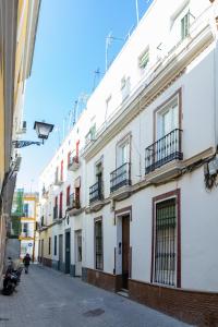 Une rangée de bâtiments blancs dans une rue dans l'établissement Apartment Triana, à Séville