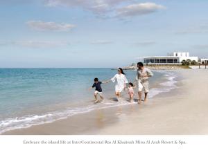 eine Familie geht am Strand spazieren in der Unterkunft InterContinental Ras Al Khaimah Resort and Spa, an IHG Hotel in Ras al Khaimah