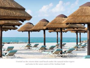 eine Gruppe Strohschirme und -stühle am Strand in der Unterkunft InterContinental Ras Al Khaimah Resort and Spa, an IHG Hotel in Ras al Khaimah