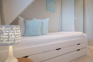 ein weißes Bett mit Kissen auf dem Zimmer in der Unterkunft Kaept32 _ 15 Mr_ Ocean II in Westerland