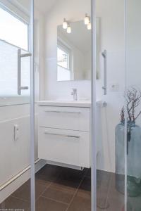 een witte badkamer met een wastafel en een spiegel bij Kaept32 _ 15 Mr_ Ocean II in Westerland