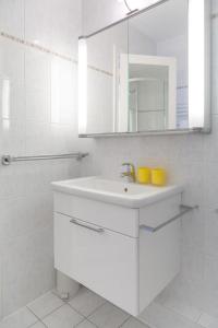 een witte badkamer met een wastafel en een spiegel bij Duen12_36 in Westerland