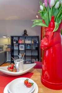 een rode vaas met bloemen en een bord eten op een tafel bij Strandgefluester _S4 _ 19_ in Westerland