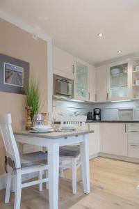 a white kitchen with a white table and chairs at Lieblingsplatz _LDH 32_1_ in Westerland (Sylt)