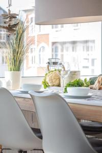stół z dwoma białymi krzesłami i stół z jedzeniem w obiekcie JhM25_7 w mieście Westerland