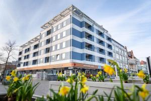 un gran edificio con flores amarillas delante de él en F23 26 Beachlife, en Westerland