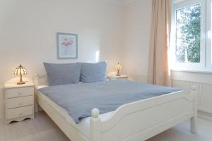 um quarto com uma cama branca com lençóis azuis e uma janela em Haus Lia Links App 3 em Tinnum