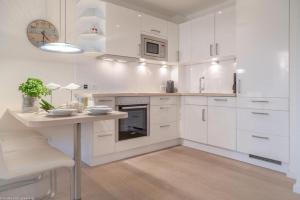 a white kitchen with white cabinets and a table at Bra5B 5 Oceanfront in Westerland