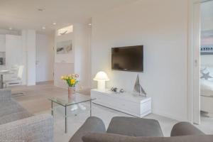 sala de estar con sofá y TV en la pared en Bra5B 5 Oceanfront, en Westerland