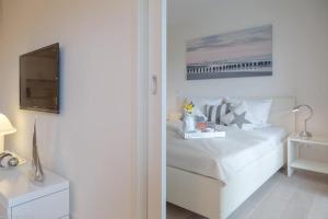a white bedroom with a bed and a television at Bra5B 5 Oceanfront in Westerland