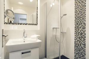 ein weißes Bad mit einem Waschbecken und einer Dusche in der Unterkunft Big Wave (Vik1 - 24) in Westerland