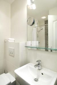 ein weißes Badezimmer mit einem Waschbecken und einem Spiegel in der Unterkunft Big Wave (Vik1 - 24) in Westerland