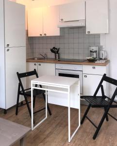 a kitchen with a white table and two chairs at Appartements Maisons Bleues in Honfleur
