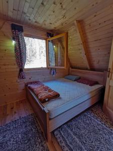 a bed in a log cabin with a window at Breeze Home Cottage in Cetinje