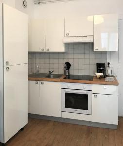 una cocina con armarios blancos y fregadero en Appartements Maisons Bleues, en Honfleur