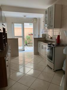 a kitchen with white appliances and a tile floor at Aconchego - lar doce lar in Poços de Caldas