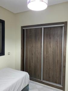 een slaapkamer met een houten kast en een bed bij Oceanica by Smir Park luxury apartment Marina Smir in M'diq