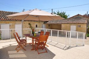 einen Tisch und Stühle mit Sonnenschirm auf einer Terrasse in der Unterkunft Repos et détente au cœur des richesses du Poitou in Vaux-en Couhé