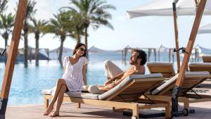un hombre y una mujer sentados en las tumbonas junto a la piscina en InterContinental Ras Al Khaimah Mina Al Arab Resort & Spa, an IHG Hotel en Ras al-Khaimah