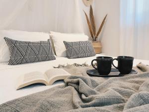 Una cama con dos tazas de café y un libro. en Villa Elenia, en Tsoukaladhes