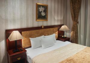 فندق منتجع قفقاز  في غابالا: غرفة في الفندق مع سرير مع وجود مصباحين على الطاولات