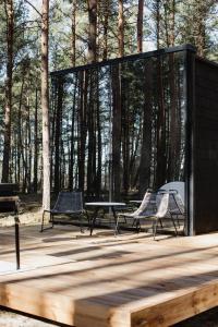 a group of chairs and a table on a wooden deck at ÖÖD Hötels Laheranna SUDU- with sauna in Punakivi