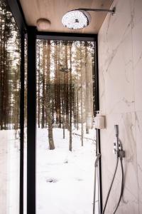 a shower in a bathroom with a view of a forest at ÖÖD Hötels Laheranna SUDU- with sauna in Punakivi