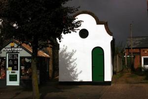 a white building with a green door on a street at Old Fire Station - quaint and quirky little home in Brandon