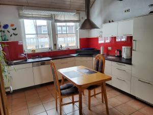 eine Küche mit roten Wänden und einem Holztisch und Stühlen in der Unterkunft Schatz-Insel in Loßburg
