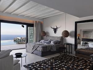 Myconian Panoptis Escape, a member of Small Luxury Hotels of the World في شاطئ إليا: غرفة نوم مع سرير وإطلالة على المحيط