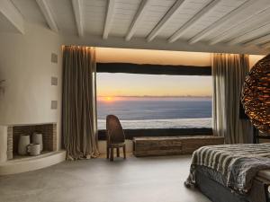 una camera da letto con finestra affacciata sull'oceano di Myconian Panoptis Escape, a member of Small Luxury Hotels of the World a Elia Beach