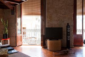 un salon avec une télévision et une grande fenêtre dans l'établissement BUBUFLATS Mossén, à Valence