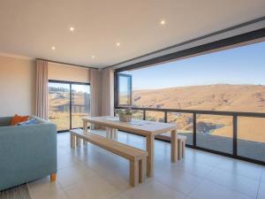 a living room with a table and a view of the desert at Highland Gate Ferox Creek in Dullstroom