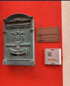 uma caixa de correio de metal no lado de uma parede vermelha em Casa Antico Barbiere em Chioggia