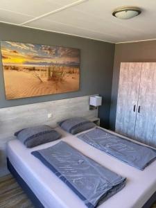 twee bedden in een slaapkamer met een schilderij aan de muur bij Appartement Zilt in Hollum