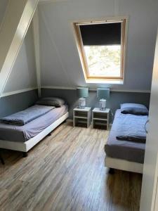 1 dormitorio con 2 camas y ventana en Appartement Zilt, en Hollum