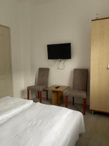 a bedroom with a bed and two chairs and a tv at Pipacs Vendégház in Bogács