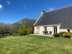 a white house with a table and chairs in a yard at Chambre d'hôtes de Kermoal-cuisine & salle de bain privées in Poullan-sur-Mer