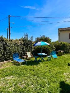 a table and chairs and an umbrella in the grass at L'ancienne étable in Brens