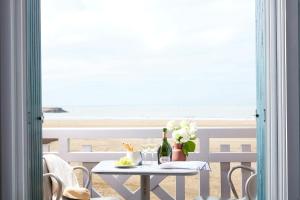 een tafel met bloemen erop met uitzicht op het strand bij Le Flaubert in Trouville-sur-Mer