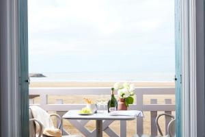 a table with flowers on it with a view of the beach at Le Flaubert in Trouville-sur-Mer