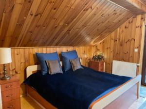 a bedroom with a bed with blue sheets and wooden walls at BESKIDIUM - uroczy dom Brenna in Brenna