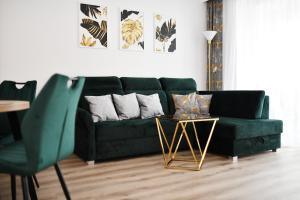 zieloną kanapę w salonie ze złotym stołem w obiekcie Apartamenty NAVIGATOR-Rezydencja Portowa 14 w Kołobrzegu
