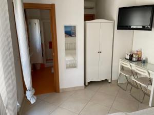 Zimmer mit einem Schreibtisch, einem TV und einem Schrank in der Unterkunft La casa di Murphy in Porto Recanati