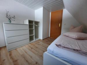 a white bedroom with a bed and a dresser at Ferienhaus Erzgebirge in Marienberg