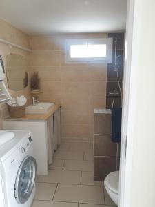 łazienka z pralką, umywalką i pralką w obiekcie Appartement le loft w Saintes-Maries-de-la-Mer